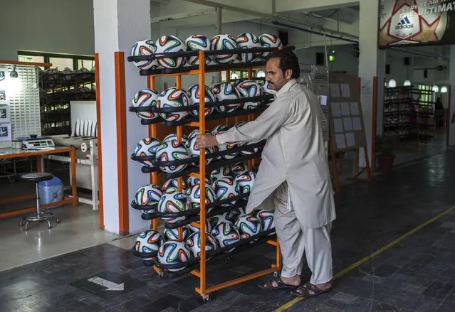 An employee takes finished balls out of the production area inside the soccer ball factory that produces official match balls for the 2014 World Cup in Brazil, in Sialkot, Punjab province May 16, 2014. (Photo by Sara Farid/Reuters)