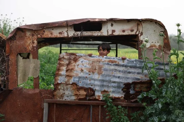 A Palestinian child peeks out of an old rusty abandoned vehicle next to his house located at the Gaza-Israel border in al-Bureij, on April 7, 2022. (Photo by Mohammed Abed/AFP Photo)