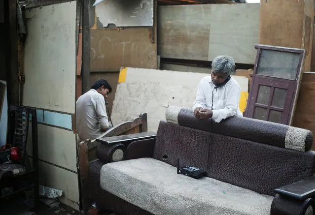 A man speaks on a pay phone in an old furniture market in New Delhi, India May 25, 2016. (Photo by Anindito Mukherjee/Reuters)