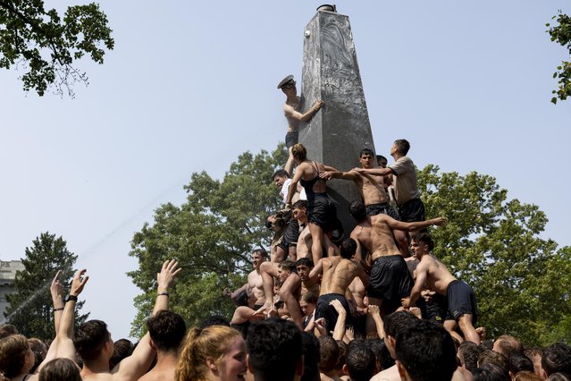 Freshmen known as “Plebes” participate in the annual Herndon Monument Climb at the U.S. Naval Academy on May 17, 2023 in Annapolis, Maryland. In just over two and a half hours, members of the 2026 midshipmen's class worked to scale the 21-foot greased monument and replace a “dixie cup” hat with the upperclassmen's hat, signifying the end of their “plebe” or first year at the academy. (Photo by Anna Moneymaker/Getty Images)