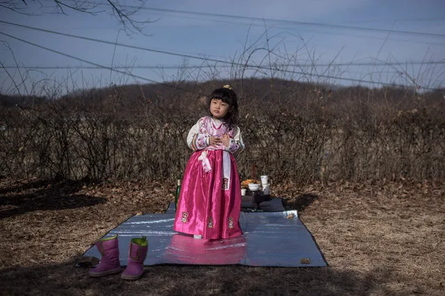 Park Yeon-Hee stands before an altar facing the North, to which prayers are offered for relatives and ancestors separated by the Korean war, near the Demilitarized Zone (DMZ) separating North and South Korea in Imjingak on January 28, 2017. On the frozen banks of the Imjin river, South Koreans divided from their families decades ago by war gathered to pay respects to their ancestors. According to tradition, Korean ceremonies for the lunar new year must be carried out by the eldest son – they lined up before an altar piled with offerings of rice cakes, fruit and fish. (Photo by Ed Jones/AFP Photo)