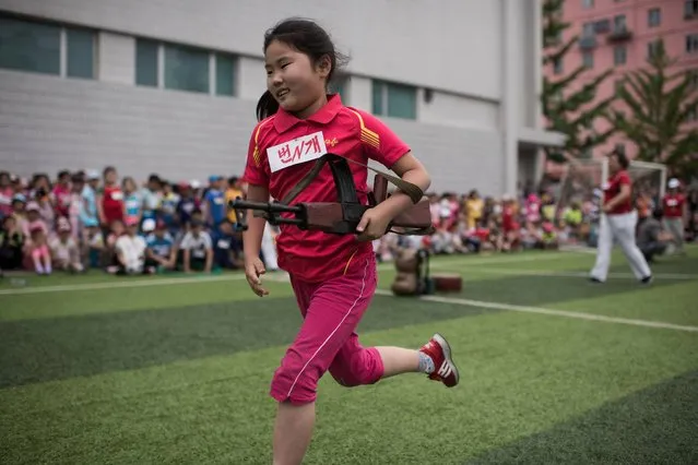 A girl carrying a mock rifle completes an obstacle course as school children take part in sports games marking “Children's Union Foundation day”, in Pyongyang on June 6, 2017. (Photo by Ed Jones/AFP Photo)