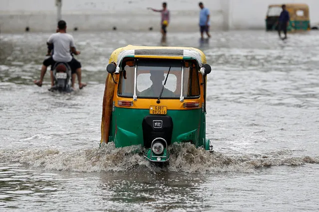 An auto-rickshaw moves through a waterlogged road after heavy rains in Ahmedabad, July 1, 2017. (Photo by Amit Dave/Reuters)