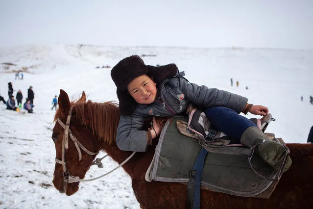 A boy climbs on a horse in Kyrgyzstan's Chui region on February 23, 2019. (Photo by Gulzhan Turdubaeva/Radio Free Europe/Radio Liberty)