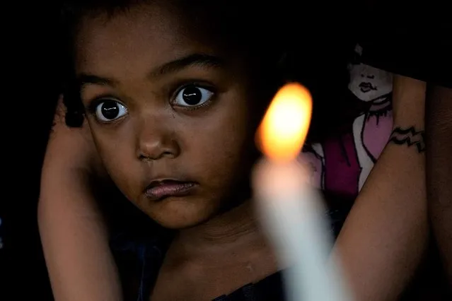 A girl stands in her home in Quilombo Mesquita, a community of descendants from slaves, during its traditional cultural-religious festival “Folia do Divino Espirito Santo”, in Cidade Ocidental, 50 km from Brasilia, Brazil, Thursday, May 12, 2022. The festival, held for more than 100 years, represents the cultural resistance of the community and the eve of the anniversary of the abolition of slavery in Brazil. (Photo by Eraldo Peres/AP Photo)