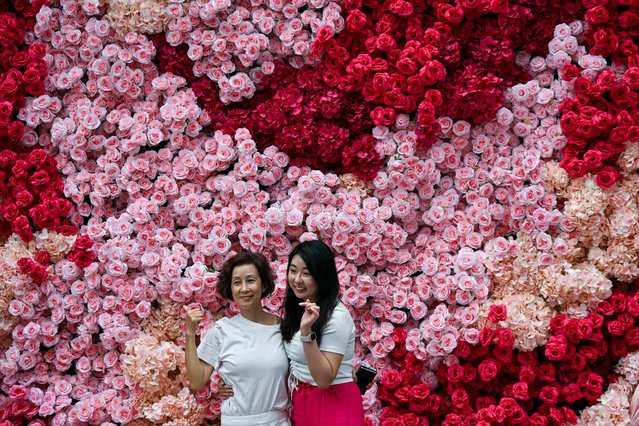 Two women pose for pictures in front of artificial roses in Kuala Lumpur on September 26,  2024. (Photo by Mohd Rasfan/AFP Photo)