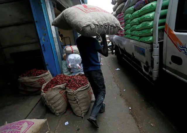 A man carries a sack of dried chilli to a truck at a main market in Colombo, Sri Lanka June 24, 2016. (Photo by Dinuka Liyanawatte/Reuters)