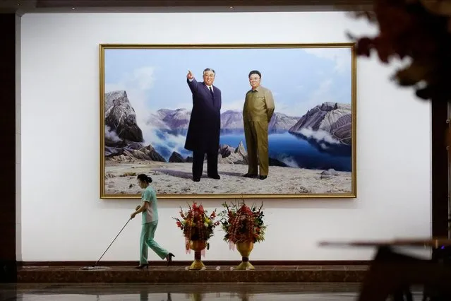 A hotel staff member mops the floor where a picture featuring portraits of the late North Korean leaders Kim Il Sung, left, and Kim Jong Il decorates the lobby wall Monday, June 19, 2017, in Pyongyang, North Korea. (Photo by Wong Maye-E/AP Photo)