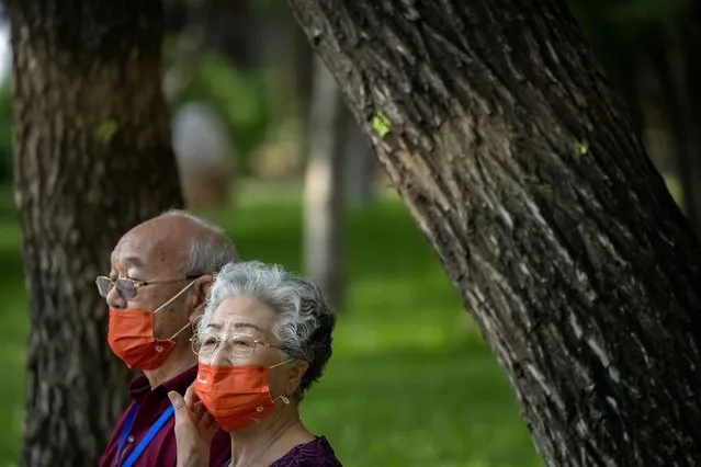 People wearing face masks sit on a bench at a public park in Beijing, Friday, July 8, 2022. (Photo by Mark Schiefelbein/AP Photo)