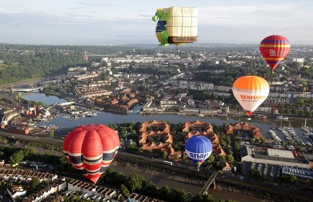 Hot air balloons take to the skies over Bristol city centre on August 6, 2012 in Bristol, England. The early morning flight of over twenty balloons over the city was organised as a curtain raiser for the four-day Bristol International Balloon Fiesta which starts on Thursday. Now in its 34th year, the Bristol International Balloon Fiesta is Europe's largest annual hot air balloon event in the city that is seen by many balloonists as the home of modern ballooning.  (Photo by Matt Cardy)