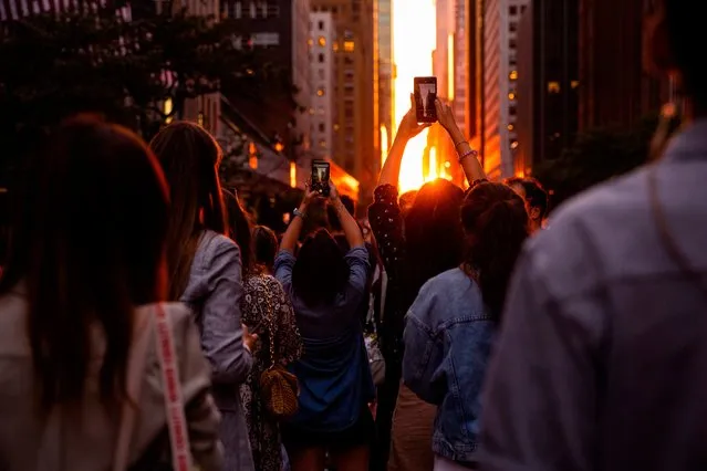 People photograph the Manhattanhenge sunset from East 42nd Street, Monday, July 11, 2022, in New York. (Photo by Julia Nikhinson/AP Photo)