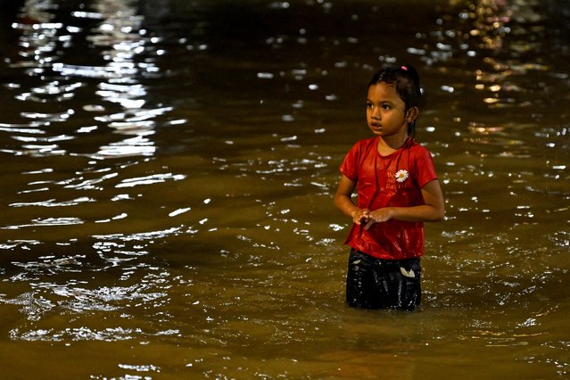 A girl wades through a flooded street after a heavy downpour in Kota Bharu, in Malaysia's Kelantan state, on November 29, 2024. Flooding in northern Malaysia and southern Thailand has killed at least eight people and forced tens of thousands from their homes, officials in both countries said on November 29. (Photo by Mohd Rasfan/AFP Photo)