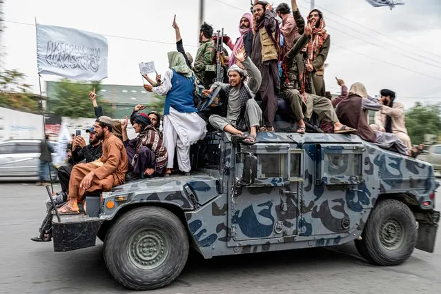 Taliban fighters hold weapons as they ride on a humvee to celebrate their victory day near the US embassy in Kabul on August 15, 2022. Taliban fighters chanted victory slogans next to the US embassy in Kabul on August 15 as they marked the first anniversary of their return to power in Afghanistan following a turbulent year that saw women's rights crushed and a humanitarian crisis worsen. (Photo by Wakil Kohsar/AFP Photo)