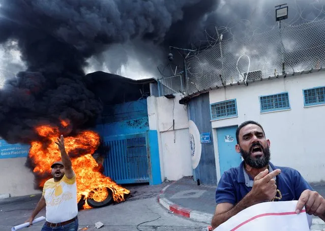 Palestinian people burn tires outside the headquarters of the United Nations Works and Relief Agency (UNRWA) during a protest demanding the UNRWA to rebuild their houses that were destroyed during the Israel-Gaza fighting in 2014, in Gaza City on September 19, 2022. (Photo by Mohammed Salem/Reuters)