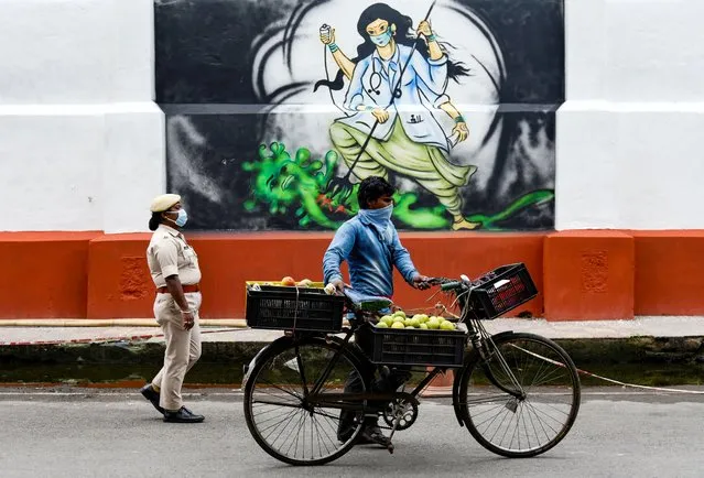 People walking past to a mural related to Coronavirus, authorities eased restrictions, during the ongoing COVID-19 nationwide lockdown, in Guwahati, Assam, India on Wednesday, 06 May 2020. (Photo by David Talukdar/NurPhoto via Getty Images)