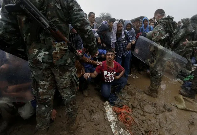 Macedonian police try to keep migrants and refugees under control before they cross the border line from Greece into Macedonia, during a raistorm near the Greek village of Idomeni, September 10, 2015. (Photo by Yannis Behrakis/Reuters)
