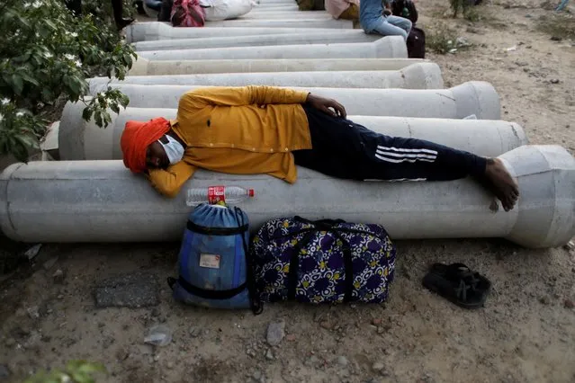 A migrant worker rests next to his belongings as he waits to cross the border to his home state of Uttar Pradesh, during an extended nationwide lockdown to slow the spread of the coronavirus disease (COVID-19), in New Delhi, India, May 16, 2020. (Photo by Adnan Abidi/Reuters)