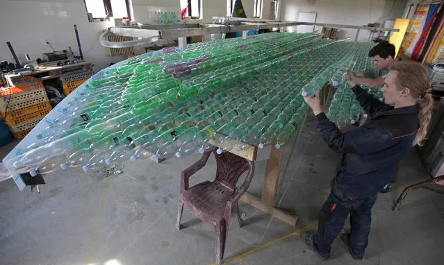 Jakub Bures (front) and Jan Kara arrange sealed plastic bottles into the shape of a boat in their garage in Nymburk April 3, 2014. (Photo by David W. Cerny/Reuters)