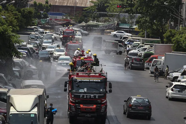 The fire department sprays disinfectant from fire engines to help curb the spread of the new coronavirus on a road Tuesday, April 21, 2020, in Yangon, Myanmar. (Photo by Thein Zaw/AP Photo)
