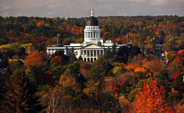 The State House is surrounded by fall foliage Monday, October 23, 2017, in Augusta, Maine. Republican Gov. Paul LePage ordered lawmakers to return to the state capitol to fix problems in the food sovereignty law and to provide funding for the Maine Office of Geographic Information Systems. Legislators are also dealing with recreational marijuana sales and the future of a new voting system approved at the polls last fall. (Photo by Robert F. Bukaty/AP Photo)
