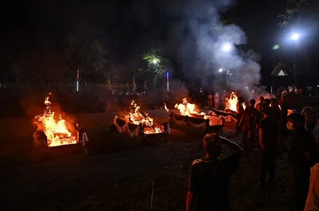People watch as the coffins of victims of the nursery mass shooting are set on fire during the cremation ceremony in Na Klang in northeastern Nong Bua Lam Phu province on October 11, 2022. (Photo by Lillian Suwanrumpha/AFP Photo)