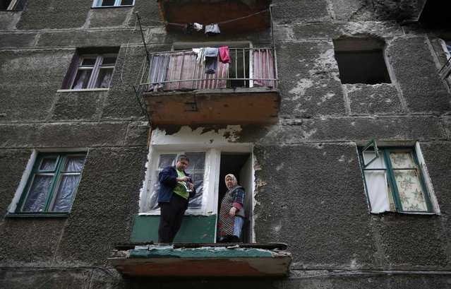 Residents stand on their balcony at a building that was damaged during a rocket shelling a day before, in the eastern Ukrainian town of Debaltseve, September 22, 2014. (Photo by David Mdzinarishvili/Reuters)