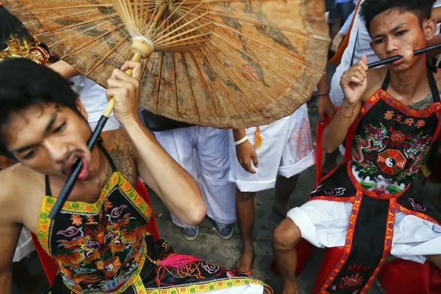 Devotees of the Chinese Bang Neow Shrine with umbrellas pierced through their cheeks get ready for a procession celebrating the annual vegetarian festival in Phuket September 29, 2014. (Photo by Damir Sagolj/Reuters)