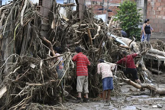 Residents search for their missing relatives in the rubble of a house destroyed by a landslide during heavy rains in Las Tejerias, Aragua state, Venezuela, on October 9, 2022. A landslide in central Venezuela left at least 22 people dead and more than 50 missing after heavy rains caused a river to overflow, Vice President Delcy Rodriguez said Sunday. (Photo by Yuri Cortez/AFP Photo)