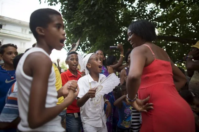 Yensy Villarreal, 9, (C), who lives in Miami, dances in the backyard of his home with friends and his mother (R) in celebration for becoming a Santero after passing a year-long rite of passage  in the Afro-Cuban religion Santeria, Havana, July 5, 2015. (Photo by Alexandre Meneghini/Reuters)