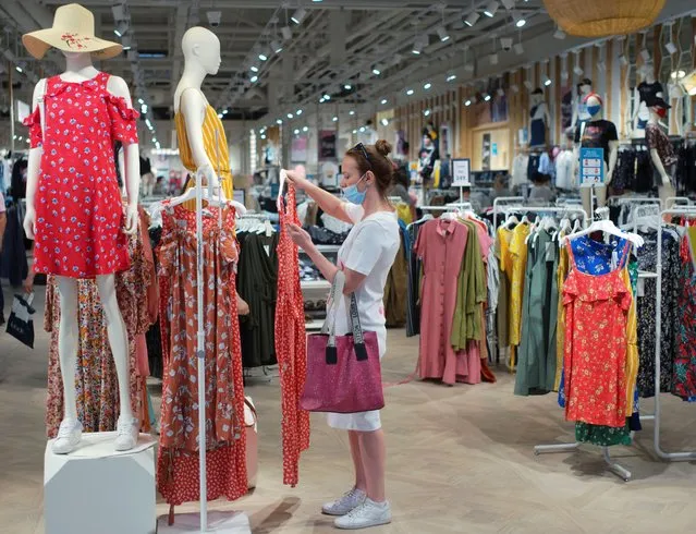 A shopper wearing a protective face mask chooses clothes at shopping mall after its reopening following loosened lockdown restrictions amid the coronavirus disease (COVID-19) outbreak in Kiev, Ukraine on June 14, 2020. (Photo by Gleb Garanich/Reuters)