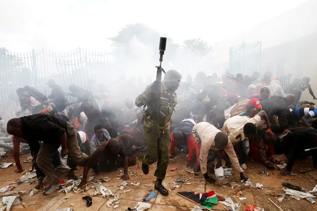 People fall as police fire tear gas to try control a crowd trying to force their way into a stadium to attend the inauguration of President Uhuru Kenyatta at Kasarani Stadium in Nairobi, Kenya, November 28, 2017. (Photo by Baz Ratner/Reuters)