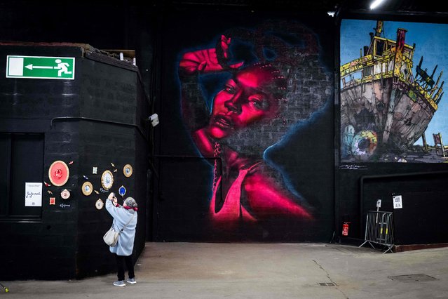People discover the works of street artists displayed as part of the exhibition “Peinture Fraiche” on October 13, 2022, at the Hall Debourg in Lyon. (Photo by Jean-Philippe Ksiazek/AFP Photo)