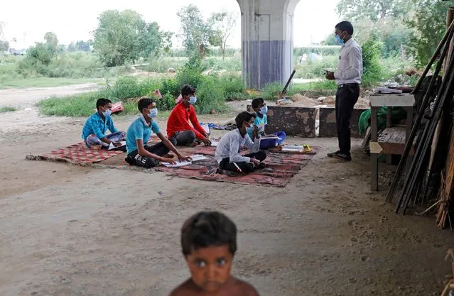 Satyendra Pal, a college student, conducts an open-air class for the students of 9th class from a slum area, who do not have access to internet facilities and miss their online lessons, after authorities closed all the schools in March following the outbreak of the coronavirus disease (COVID-19), in New Delhi, India, July 8, 2020. (Photo by Adnan Abidi/Reuters)
