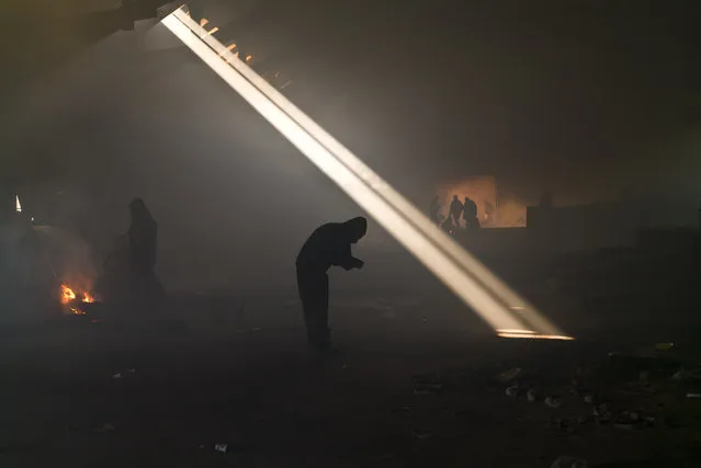 A group of migrants, left, gather around a fire to warm themselves in an abandoned warehouse in Belgrade, Serbia, on January 30, 2017. Hundreds of migrants have been sleeping in freezing conditions in central Belgrade looking for ways to cross the heavily guarded EU borders. (Photo by Muhammed Muheisen/AP Photo)