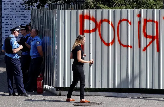 Police stand guard as an activist sprays the word “Russia” on the barrier around Ukrainian television channel “Inter”, which protesters say has an anti-Ukrainian stance, in Kiev, Ukraine September 5, 2016. (Photo by Gleb Garanich/Reuters)