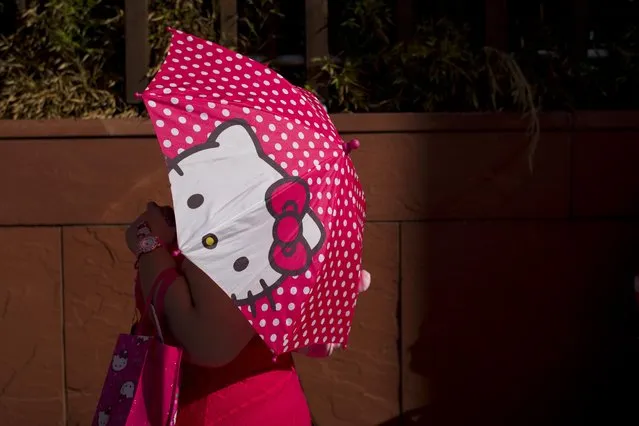 A woman uses a Hello Kitty umbrella to shelter from the sun while waiting in line for the Hello Kitty Con, the first-ever Hello Kitty fan convention, held at the Geffen Contemporary at MOCA Thursday, October 30, 2014, in Los Angeles. (Photo by Jae C. Hong/AP Photo)