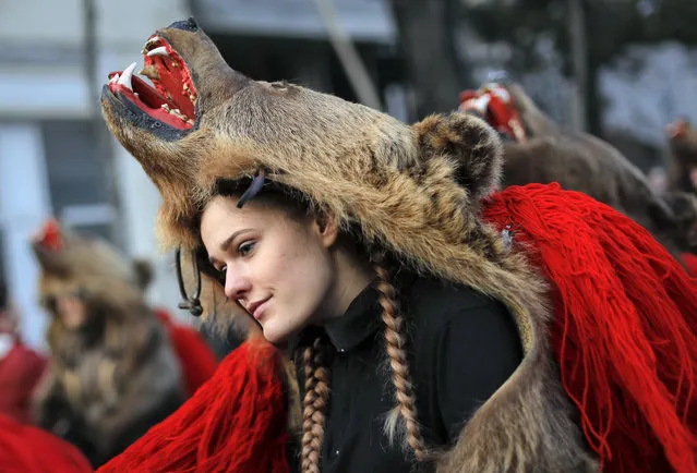 A girl wearing a bear costume dances during an annual ritual in Piatra Neamt, northern Romania, Thursday, December 28, 2017. The tradition, which originates in pre-Christian times when dancers wearing colored costumes or animal furs went from house to house in villages singing and dancing to ward off evil, has moved to Romania's cities, where dancers travel to perform the ritual for money. (Photo by Vadim Ghirda/AP Photo)