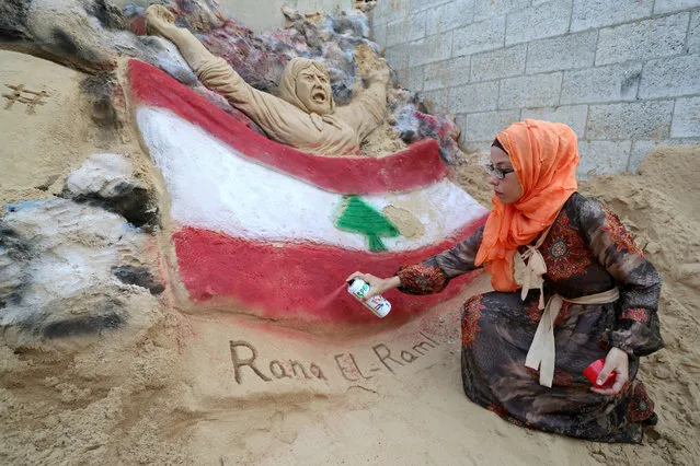 Rana El-Ramlawi, a Palestinian artist, paints the colors of the Lebanese flag on a sand sculpture to show solidarity with the Lebanese people following Beirut's massive blast, in Gaza City on August 11, 2020. (Photo by Mohammed Salem/Reuters)
