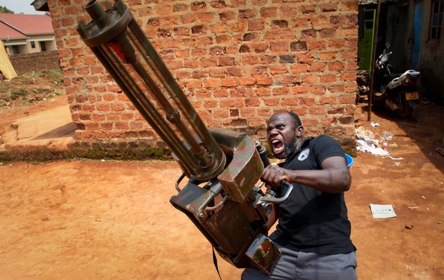 In this photo taken Wednesday, September 7, 2016, actor Daudi Bisaso rehearses with a mock machine gun, at the “Wakaliwood” studios in the Wakaliga slum of Kampala, Uganda. Deep in this Kampala slum at a tin-roofed collection of houses known as Wakaliwood, is the engine of Uganda's tiny film industry and the source of $200-budget movies and a glimmer of fame. (Photo by Stephen Wandera/AP Photo)