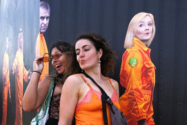 Revellers pose by a graphic by Block 9 and Led by Donkeys showing former British Prime Minister Liz Truss and other political figures and billionaires with the words “Send them to Mars while we party on Earth” on it, at Glastonbury Festival at Worthy Farm in Pilton, Somerset, Britain, on June 26, 2025. (Photo by Jaimi Joy/Reuters)