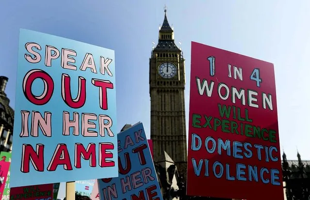 People hold banners during a demonstration against domestic violence near Big Ben in the lead up to  International Women's Day, in London on Tuesday. Avon, Refuge and Women's Aid are launching a new campaign called “Speaking Out In Her Name” to raise awareness of domestic violence. (Photo by Kirsty Wigglesworth/Associated Press)
