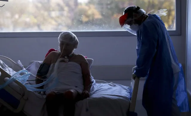 A health worker attends to a patient in an intensive care unit designated for people infected with COVID-19 at a hospital in Buenos Aires, Argentina, Friday, October 2, 2020. (Photo by Natacha Pisarenko/AP Photo)