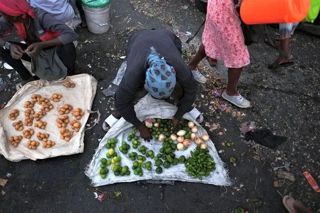 A street market vendor gathers fresh produce days after Haiti police blocked streets and broke into the airport during a protest demanding justice for fellow police officers killed by armed gangs, in Port-au-Prince, Haiti on January 29, 2023. (Photo by Ricardo Arduengo/Reuters)