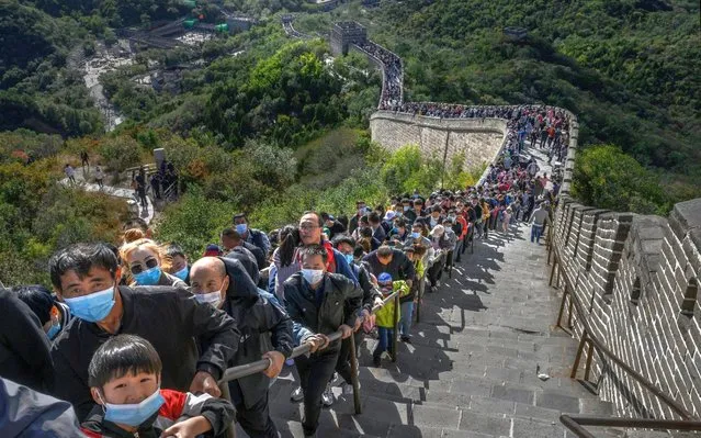 Chinese tourists line up at a bottleneck as they climb a section of the Great Wall at Badaling after tickets sold out during the “Golden Week” holiday on October 4, 2020 in Beijing, China. Officials are expecting the Golden Week holiday to boost China's consumer economy as people were encouraged to use the 8-day break to travel and spend. Tourist sites including the Great Wall were packed, with tickets selling out most days given pandemic restrictions and capacity capped at 75%. (Photo by Kevin Frayer/Getty Images)
