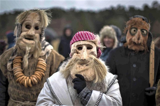 Revellers wearing traditional carnival masks take part in Shrovetide celebrations, in Rumsiskes village, some 89 kilometres (56 miles) north of Vilnius, Lithuania, Saturday, February 18, 2023. A strange scenario took place in this central Lithuania village this weekend as chanting devils, goats, witches and others filled the streets to chase winter away. Shrovetide is a traditional Lithuanian holiday marking the end of winter. (Photo by Mindaugas Kulbis/AP Photo)