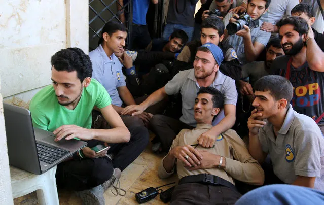 Civil Defence members, also known as the “White Helmets”, who have been nominated for the 2016 Nobel Peace Prize, gather around a laptop as they wait the announcemenet of the winner, in a rebel held area of Aleppo, Syria October 7, 2016. (Photo by Abdalrhman Ismail/Reuters)