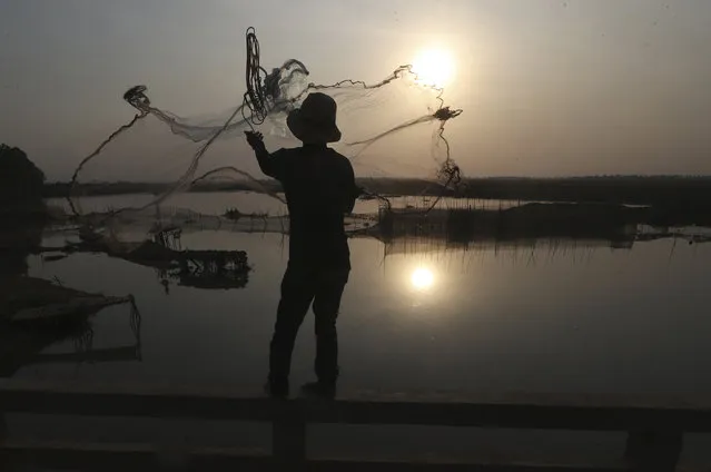 A fisherman casts his net into a lake on the outskirts of Phnom Penh, Cambodia, Monday, February 6, 2023. (Photo by Heng Sinith/AP Photo)