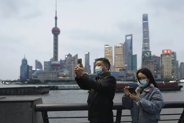Visitors wearing masks to protect themselves from the coronavirus take photos at the Bund in Shanghai, China, Monday, November 23, 2020. (Photo by AP Photo/Stringer)