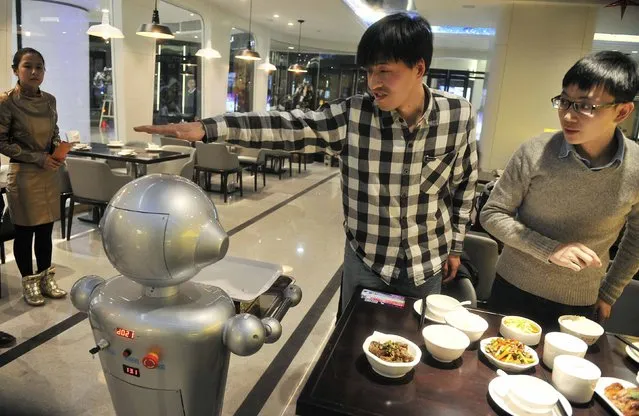 A man gestures to a robot at a restaurant in Hefei, Anhui province, December 26, 2014. (Photo by Reuters/Stringer)