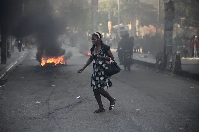 A woman walks close to burning tires after riots happened during a demonstration against the preliminary results of the presidential elections in Port-au-Prince, Haiti, November 20, 2015. (Photo by Andres Martinez Casares/Reuters)